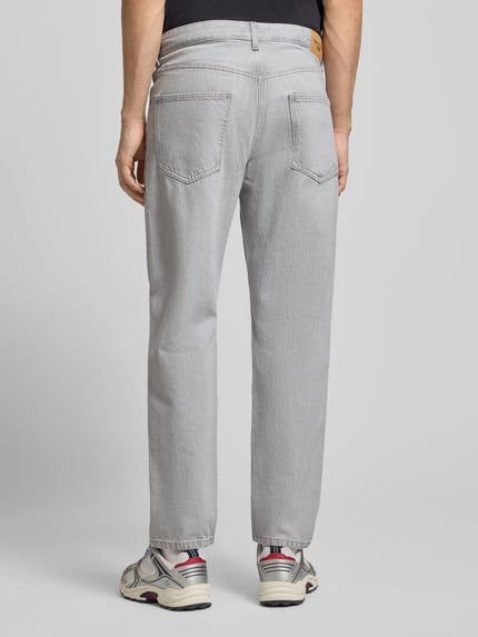 Männermodel draagt Loose fit jeans uit puur katoen Model 'RUNNE' van Marc O'Polo Denim in grijs denimlook met 5-pocketmodel, labelpatch en knoop- en ritssluiting, Ganzkörperansicht Rückansicht.