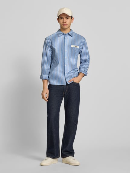 Männermodel trägt Regular Fit Freizeithemd mit Kentkragen Modell 'Drift' von PROHIBITED in Blau gestreift aus reiner Baumwolle, Ganzkörperansicht von vorne.