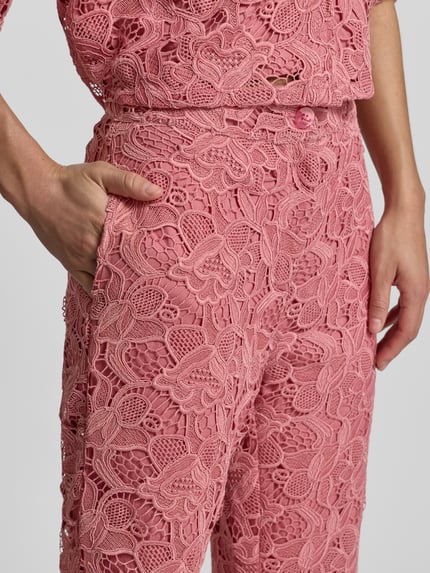 Frauenmodel trägt Stoffhose aus Spitze mit Eingrifftaschen von Jake*s Collection in Rosa mit floraler Textur, Nahaufnahme Oberkörper. Damen Stoffhose, Straight Fit, Knopf-Reißverschluss, Bundweite 36 cm, Innenbeinlänge 83 cm.