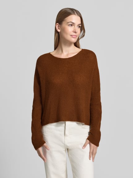 Frauenmodel trägt Oversized Wollpullover aus Alpaka-Mix von DRYKORN in Braun, Ripp-Optik, weitem Schnitt, Rundhalsausschnitt, Ganzkörperansicht von vorne.