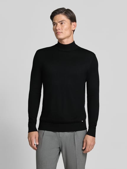 Männermodel trägt Rollkragenpullover mit Viskose-Anteil von MARKUP in Schwarz, gerader Schnitt, gerippte Abschlüsse, Ganzkörperansicht von vorne.