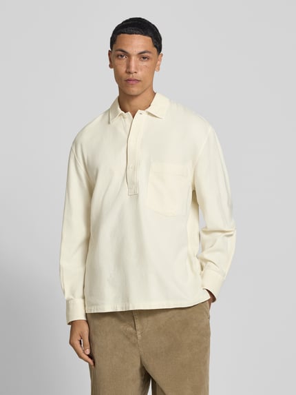 Männermodel trägt Regular Fit Poloshirt mit Brusttasche von Officine Générale in Beige, reine Baumwolle, Langarm, Ganzkörperansicht von vorne.