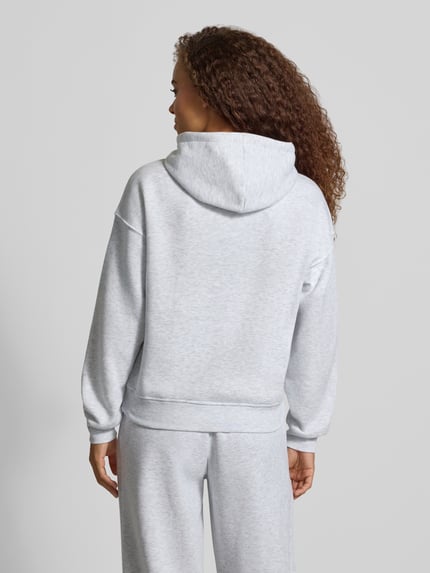 Frauenmodel trägt Regular Fit Hoodie aus Baumwoll-Mix Modell 'BEST' von ONLY in hellgrau mit glatter Textur, Ganzkörperansicht Rückansicht. Damen Hoodie von ONLY.