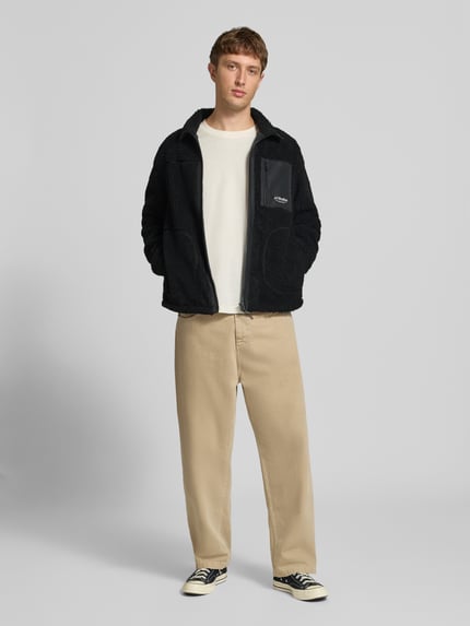 Männermodel trägt schwarze Fleecejacke mit Stehkragen Modell 'SOHO' von JACK & JONES, Teddyfell, Reißverschluss, Ganzkörperansicht von vorne.