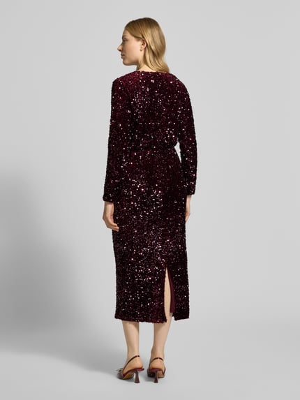 Frauenmodel trägt Midikleid mit V-Ausschnitt Modell 'FAITH' von Vila in Dunkelrot mit Pailletten, tailliert, blickdicht, Ganzkörperansicht Rückansicht.