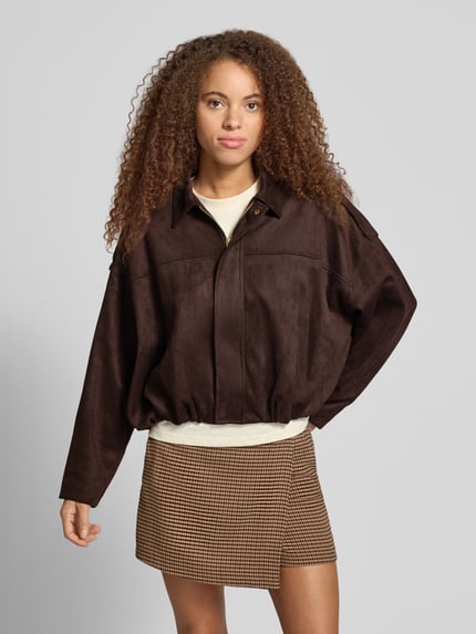 Frauenmodel trägt Kurzmantel mit Schulterklappen von ONLY in Dunkelbraun, sichtbare Textur, kombiniert mit gemusterter Rock, Ganzkörperansicht von vorne, Damen Kurzmantel von ONLY