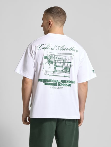 Männermodel trägt Regular Fit T-Shirt mit Logo-Print von ANOTHER COTTON LAB, Baumwoll-Mix, weiß mit grünem Print, Ganzkörperansicht Rückansicht.
