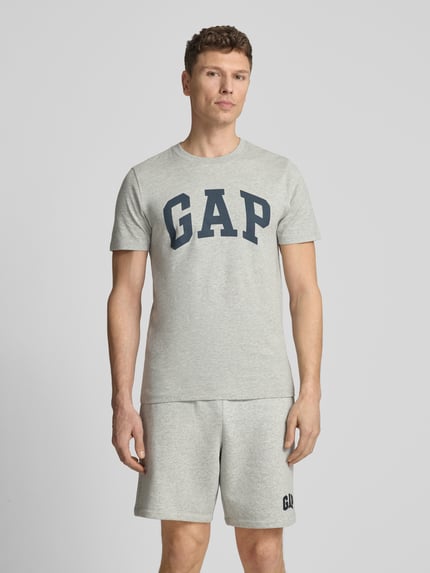 Männermodel trägt T-Shirt mit Logo und Rundhalsausschnitt von GAP, Herren T-Shirt aus Reine Baumwolle, Regular-Fit, hellgrau, Ganzkörperansicht von vorne. Rückenlänge bei Größe M 72 cm