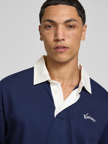 Männermodel trägt Regular Fit Poloshirt aus Baumwolle von Kenzo in Dunkelblau mit kontrastivem Kragen und Label-Stitching, Nahaufnahme Oberkörper.