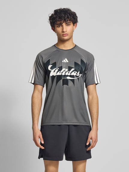 Männermodel trägt Regular Fit T-Shirt mit Label Print von adidas Sportswear, Optik: Unifarben, Kontraststreifen, Kurzarm, Ganzkörperansicht von vorne.