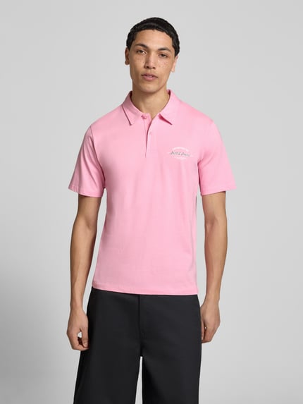 Männermodel trägt Poloshirt mit Label-Print Modell 'BRANDON' von Jack & Jones aus reiner Baumwolle, Regular-Fit, Polokragen, kurze Knopfleiste, Rückenlänge bei Größe M 71 cm, Ganzkörperansicht von vorne.