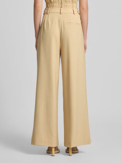 Vrouwenmodel draagt Loose Fit Pants met steekzakken model 'stacy' van Gestuz, materiaalmix met viscose, recht model, strookzak aan de achterkant. Volledige lichaamsaanzicht achteraan.