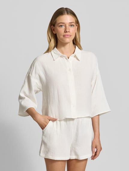 Frauenmodel trägt Loose Fit Hemdbluse aus reiner Baumwolle Modell 'NATALI' von Vero Moda, Optik: Unifarben, Materialverarbeitung: Seersucker, 3/4-Arm, Hemdkragen, einreihige Knopfleiste, Ganzkörperansicht von vorne.