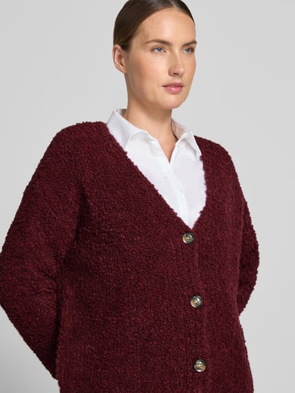 Frauenmodel trägt Relaxed Fit Strickjacke aus Woll-Viskose-Mix Modell 'Sofia' von ZABAIONE in Bordeaux, Knopfleiste, Nahaufnahme Oberkörper. Damen Strickjacke, V-Ausschnitt, langärmliges Design, weiche strukturierte Oberfläche, Rückenlänge S/M 62 cm, Ärmellänge 45 cm.