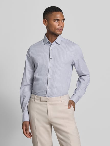 Männermodel trägt Slim Fit Business-Hemd mit Kentkragen von OLYMP Level Five, Baumwoll-Mix mit Stretch-Anteil, feine Streifen, Knopfleiste, Ganzkörperansicht von vorne.