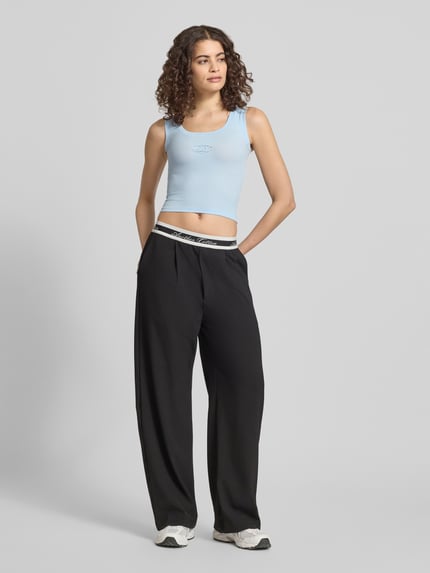 Frauenmodel trägt Slim Fit Top mit Logo-Detail von ANOTHER COTTON LAB in Hellblau, glatter elastischer Baumwoll-Mix, Rundhalsausschnitt, Ganzkörperansicht von vorne.