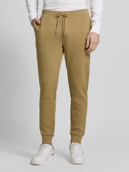 Männermodel trägt 'Tapered Sweatshorts aus Baumwoll-Mix' von Polo Ralph Lauren, effen look, tapered pasvorm, logostitching, tunnelkoord, elastische boord, zij-steekzakken, achterzak, sweat materiaalverwerking, katoenmix, detailaufnahme onderlichaam