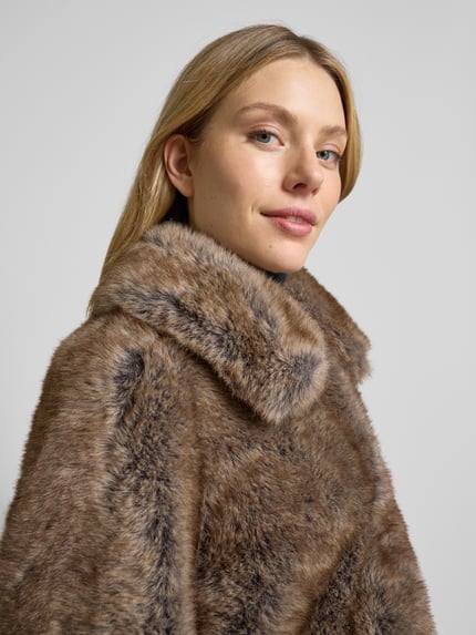 Frauenmodel trägt Jacke aus Kunstfell mit Umlegekragen Modell 'BOLA' von Mango, braune Farbnuancen, Regular Fit, Nahaufnahme Oberkörper. Rückenlänge 47 cm, Schulterbreite 37 cm, Brustweite 54 cm, Ärmellänge 57 cm.