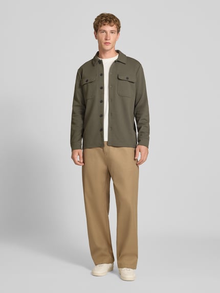 Männermodel trägt Relaxed Fit Hemdjacke mit Viskose-Anteil Modell 'NEWKODYL' von ONLY in Oliv, beige Hose, dezente Textur, Ganzkörperansicht von vorne. Herren Hemdjacke von ONLY & SONS.