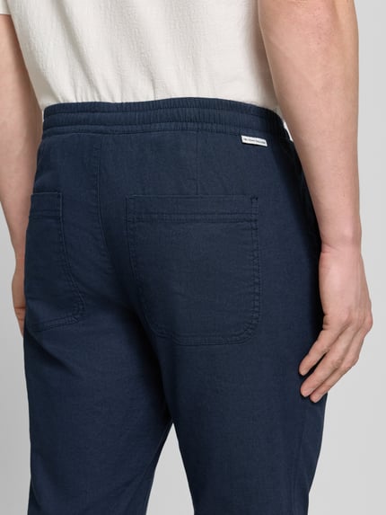 Männermodel trägt 'Gerade Hose aus Leinen-Baumwoll-Mix' von Tom Tailor, efekt: jednolity kolor, naszywka z logo, wpuszczane i tylne kieszenie, mieszanka lnu i bawełny, prosty krój, średni stan, zapięcie na guzik i ukryty zamek błyskawiczny, detaliczny widok tylnej części, Ganzkörperansicht Rückansicht.