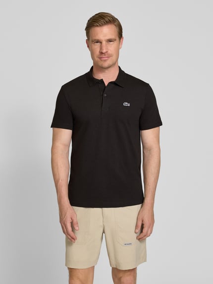 Männermodel trägt Regular Fit Poloshirt aus Baumwoll-Mix von Lacoste, Optik: Unifarben, Logo-Patch, Polokragen, Kurzarm, Ganzkörperansicht von vorne.
