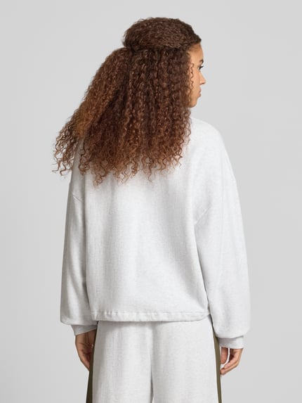 Frauenmodel trägt jasnoszarą bluzę z bawełny OH APRIL Boxy Fit Sweatshirt mit Knopfleiste Modell 'Aven', wyhaftowane logo, widok całej sylwetki z tyłu