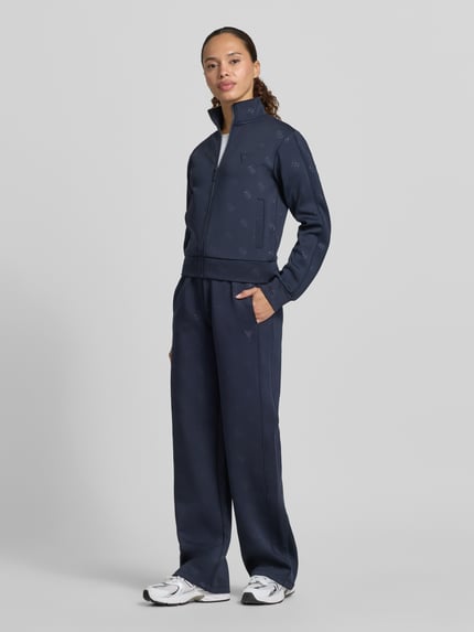 Kobiece model prezentuje Sweatjacke mit Logo-Muster Modell 'CALISTA' od Guess Activewear, granatowy, krój regular fit, zdjęcie całopostaciowe z przodu