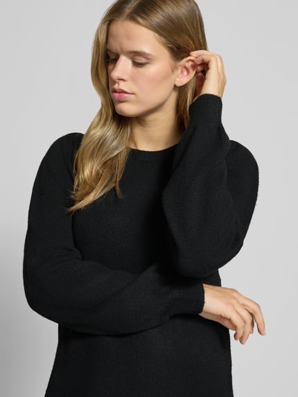Frauenmodel trägt schwarzes Strickkleid mit Label-Detail von PIECES, weiche Struktur, einfarbig, Damen Freizeitkleid, Nahaufnahme Oberkörper.