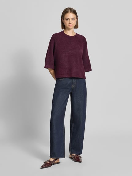 Frauenmodel trägt Regular Fit Pullover mit 3/4-Ärmeln Modell 'SIMONI' von ONLY in Dunkellila, lockere Passform, Damen Pullover, Ganzkörperansicht von vorne.