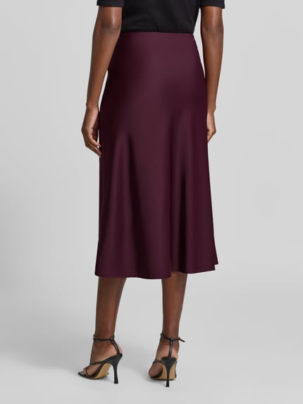 Frauenmodel trägt Midirock mit elastischem Bund Modell 'PELLA' von YAS, bordeauxfarben, Satin, A-Linie, Ganzkörperansicht Rückansicht.