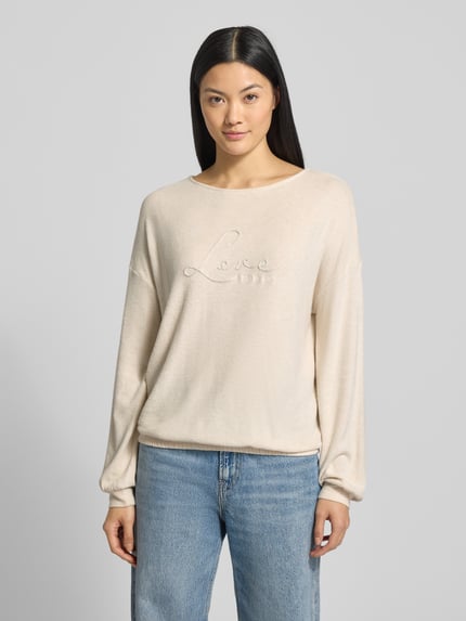 Frauenmodel trägt Regular Fit Sweatshirt aus Viskose-Mix von Tom Tailor in Melange-Optik, Statement-Stitching, Label-Print, Rundhals, Langarm, elastischer Rumpfabschluss, Materialverarbeitung Sweat, dezente helle Farbgebung, Ganzkörperansicht von vorne.