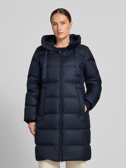 Frauenmodel trägt Regular Fit Daunenmantel mit Label-Print von Marc O'Polo in Dunkelblau mit glatter, gesteppter Textur, Ganzkörperansicht von vorne. Damen Daunenmantel von Marc O'Polo