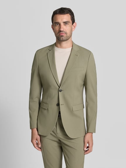 Männermodel trägt Slim Fit Sakko mit Viskose-Anteil Modell 'LIAM' von Selected Homme in hellem Oliv, glatte Textur, Ganzkörperansicht von vorne. Herren Sakko von Selected Homme.