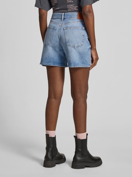 Frauenmodel trägt Regular Fit Shorts in Denim-Optik von Anine Bing, niebieski odcień, bawełna, 5 kieszeni, krój regular fit, zapięcie na guzik i zamek błyskawiczny, długość wewnętrzna nogawki 38 cm, szerokość w rozmiarze 27: 15 cm, Ganzkörperansicht Rückansicht