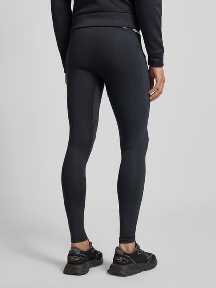 Männermodel trägt Leggings mit elastischem Bund und Logo von Under Armour in Schwarz, körpernahe Passform, Rückansicht, Ganzkörperansicht