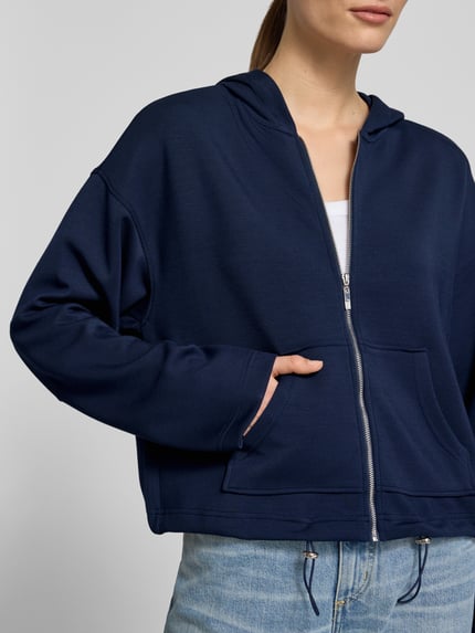 Frauenmodel trägt Regular Fit Sweatjacke mit Kapuze von Christian Berg Woman in Dunkelblau, Elastischer-Material-Mix mit Modal-Anteil, Kängurutasche, Bund mit Tunnelzug, Nahaufnahme Oberkörper.