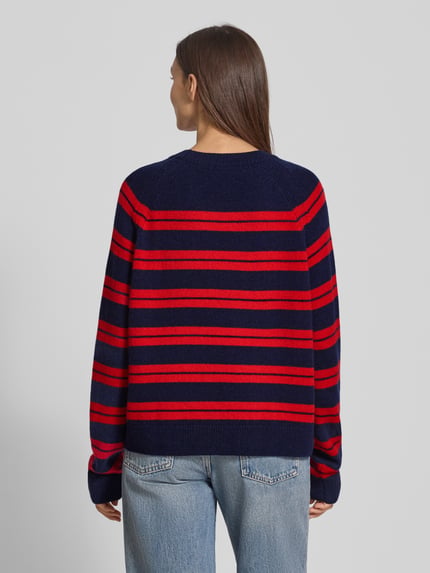Vrouwenmodel draagt Loose Fit Strickpullover aus reinem Woll-Mix Modell 'LILIRIAA FINE STRIPES' van Armedangels, donkerblauw met rode strepen, grof gebreid, ronde hals, ribboorden, lange mouwen, label patch. Ganzkörperansicht rugaanzicht.