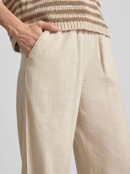 Vrouwenmodel draagt Weite Hose aus Baumwoll-Leinen-Mix Modell 'CAIA' van Vero Moda, effen kleuren, wide leg pasvorm, tunnelkoord, elastische boord, zij-steekzakken, mix van katoen en linnen, close-up taille en heupen.