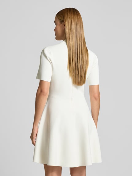 Frauenmodel trägt Polokleid mit kurzer Knopfleiste Modell 'RONDAA' von Ted Baker in Weiß, taillierter Schnitt, Viskose-Mix, Ganzkörperansicht Rückansicht.