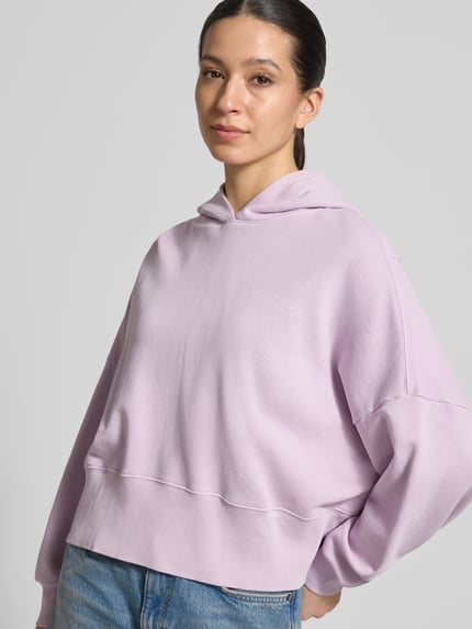 Modelka nosi Relaxed Fit Hoodie aus reiner Baumwolle von Marc O'Polo, efekt: jednolity kolor, nadruk z logo, kaptur, długi rękaw, dzianina dresowa z bawełny, prążkowane zakończenia, Ganzkörperansicht von vorne.
