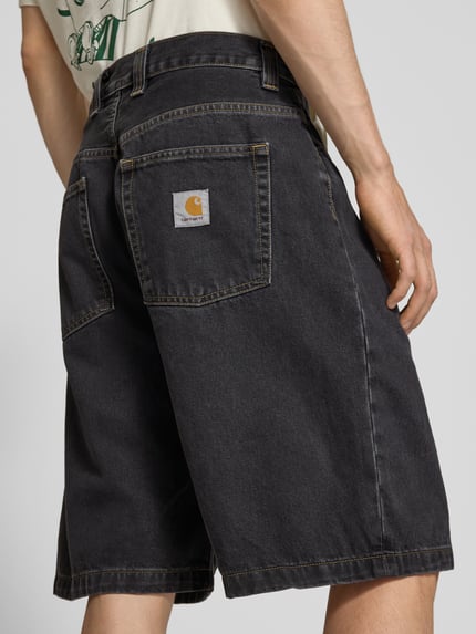Männermodel trägt Jeansshorts mit Eingrifftaschen Modell 'Brandon' von Carhartt Work In Progress in Schwarz, Reine Baumwolle, Relaxed-Fit, Ganzkörperansicht Rückansicht. Bundweite bei Größe M: 44 cm, Innenbeinlänge bei Größe M: 25 cm.