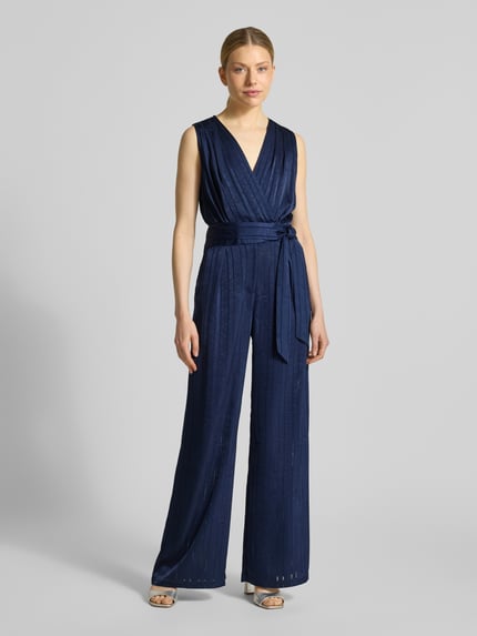 Frauenmodel trägt Jumpsuit mit Strukturmuster Modell 'Telma' von SUNCOO PARIS in Dunkelblau, taillierte Passform, V-Ausschnitt, Ärmelloses-Design, Stoffband, Ganzkörperansicht von vorne.