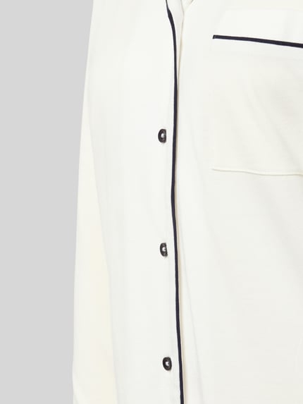 Frauenmodel trägt Regular Fit Pyjama-Oberteil mit Brusttasche von Christian Berg Woman aus Baumwoll-Modal-Mix, Knopfleiste, Detailaufnahme.