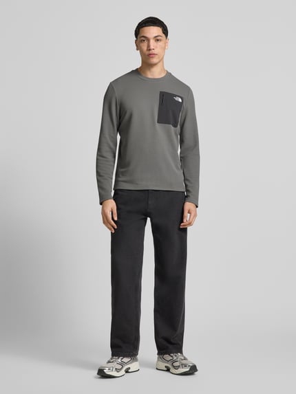 Männermodel trägt Langarmshirt mit Napoleontasche Modell 'KECHA' von The North Face in Grau, Elastischer-Material-Mix, Gerader-Schnitt, Rundhalsausschnitt, Label-Detail, Rückenlänge bei Größe M 67 cm, Ganzkörperansicht von vorne.
