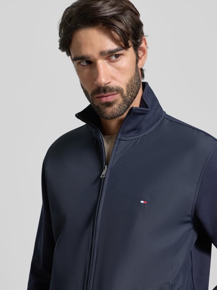 Männermodel trägt Regular Fit Blouson aus Baumwoll-Mix von Tommy Hilfiger in Dunkelblau, unifarben, Stehkragen, Nahaufnahme Oberkörper.