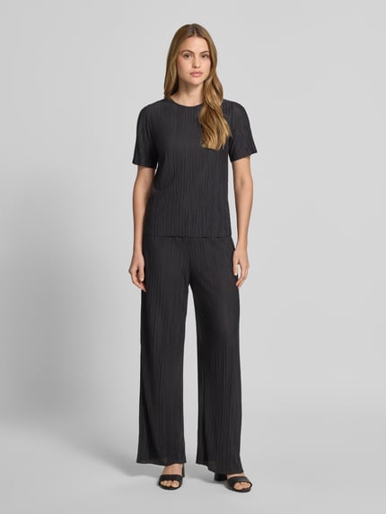 Frauenmodel trägt schwarze Wide Leg Hose mit Plisseefalten Modell 'PLISA' von Vila aus Material-Mix mit Viskose-Anteil, Ganzkörperansicht von vorne.