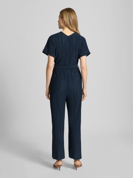 Modelka nosi Jumpsuit mit Plisseefalten und Bindegürtel Modell 'Pe44arl' od ZABAIONE w kolorze granatowym, tkanina plisowana, pasek, dekolt w serek, krój slim fit, długość tyłu w rozmiarze S: 38 cm, szerokość w rozmiarze S: 39 cm, długość całkowita w rozmiarze S: 145 cm, długość wewnętrzna nogawki w rozmiarze S: 69 cm, widok całej sylwetki z tyłu.