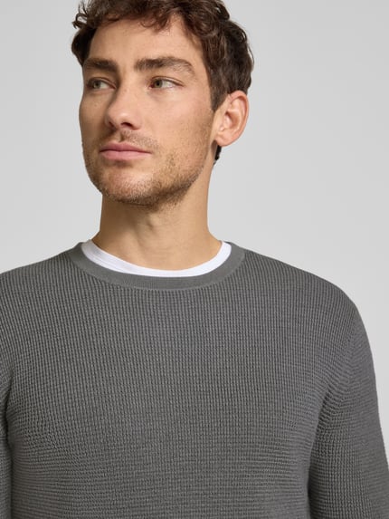 Männermodel trägt Strickpullover mit gerippten Abschlüssen Modell 'Connor' von Tiger Of Sweden, grauer Woll-Baumwoll-Mix, Nahaufnahme Oberkörper.
