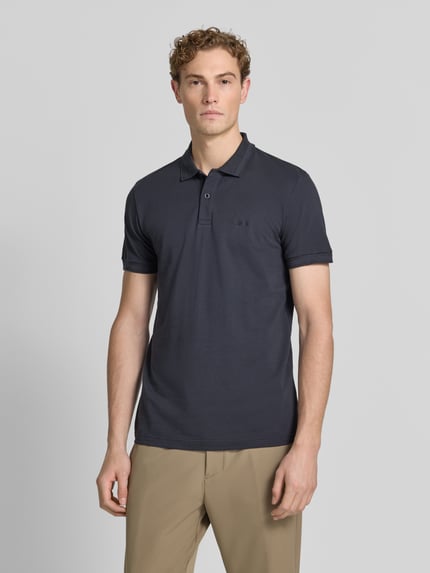 Męski model nosi koszulkę polo Regular Fit Poloshirt aus reiner Baumwolle model 'PIO 1' od BOSS Green w kolorze ciemnoszarym, gładka faktura, widok całej sylwetki od przodu.