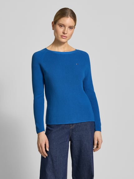 Frauenmodel trägt Regular Fit Strickpullover aus reiner Baumwolle von Tommy Hilfiger, Strickoptik, Blau, Logo-Schriftzug, Ganzkörperansicht von vorne.